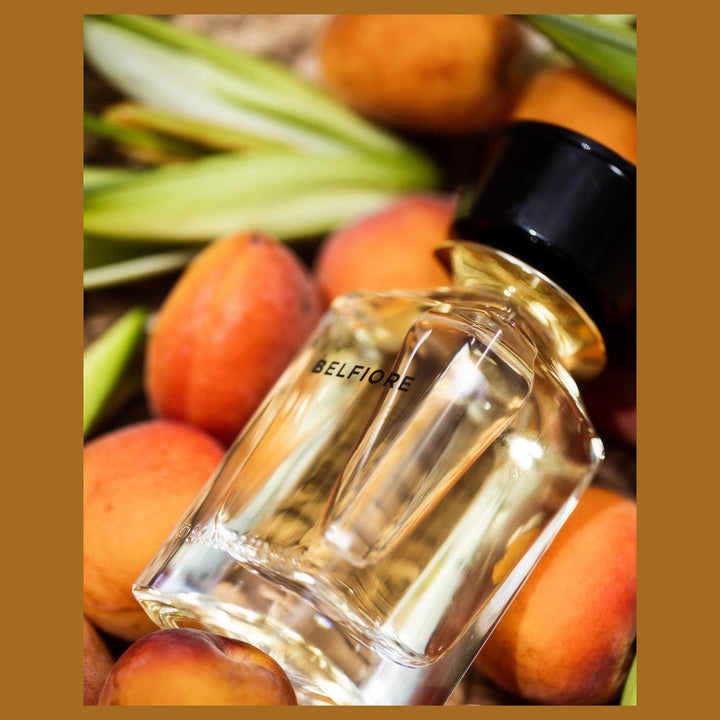 Oman Luxury Belfiore Eau de Parfum bottle among fresh apricots and green leaves