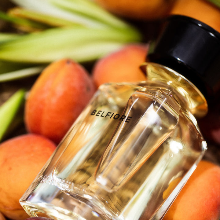 Oman Luxury Belfiore Eau de Parfum bottle among fresh apricots and green leaves