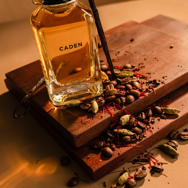 Oman Luxury Caden Eau de Parfum bottle on stacked wood with cardamom, coffee and saffron
