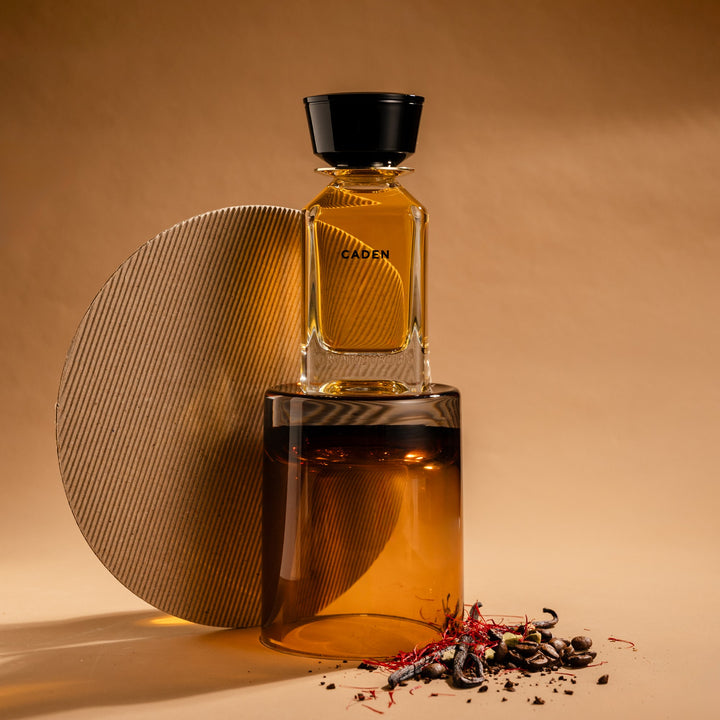 Oman Luxury Caden Eau de Parfum bottle against a stone disc with scattered spice
