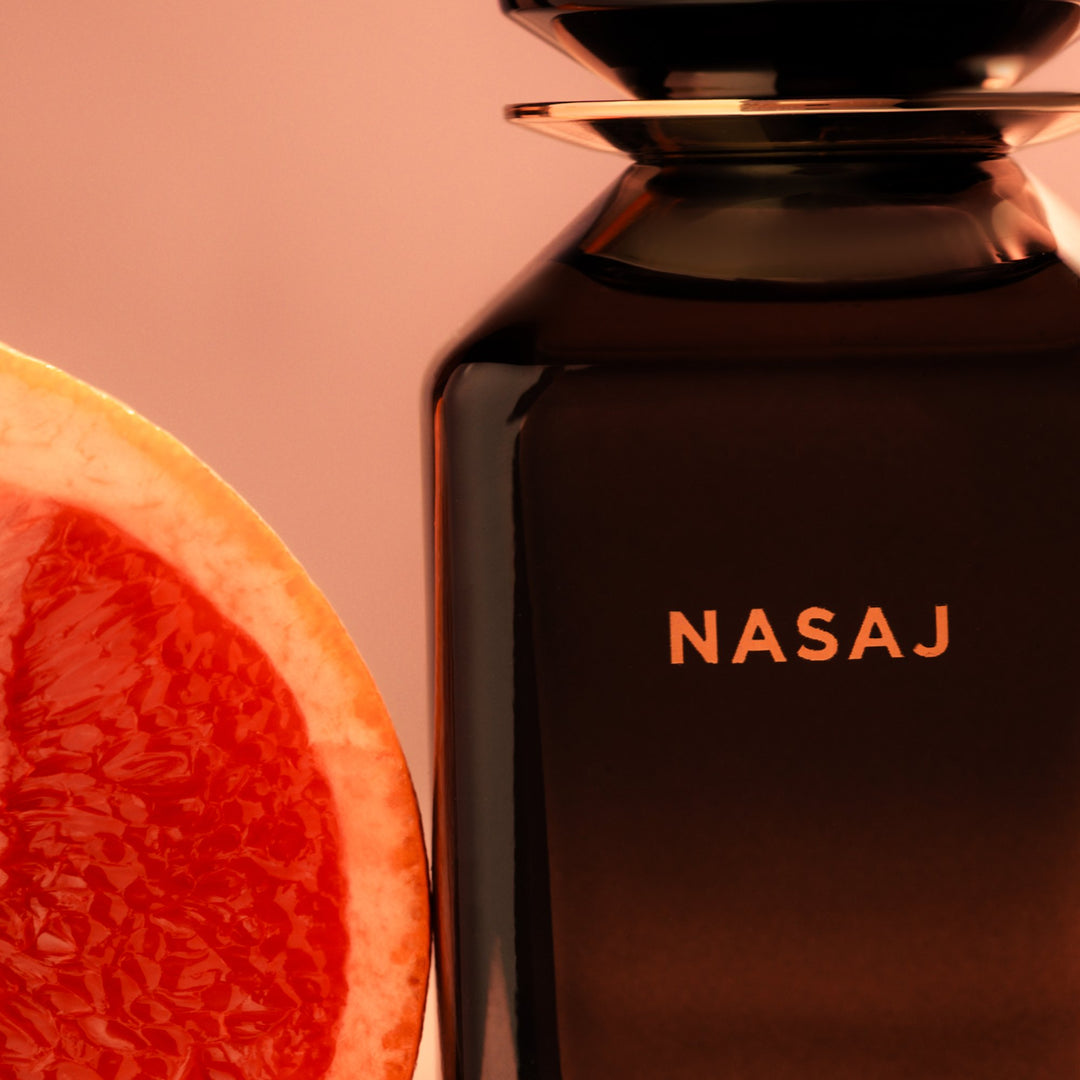 Oman Luxury Nasaj Eau de Parfum bottle close up beside a halved pink grapefruit