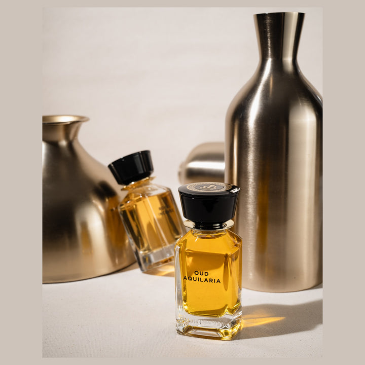 Oman Luxury Oud Aquilaria Eau de Parfum bottle beside brushed brass vessels
