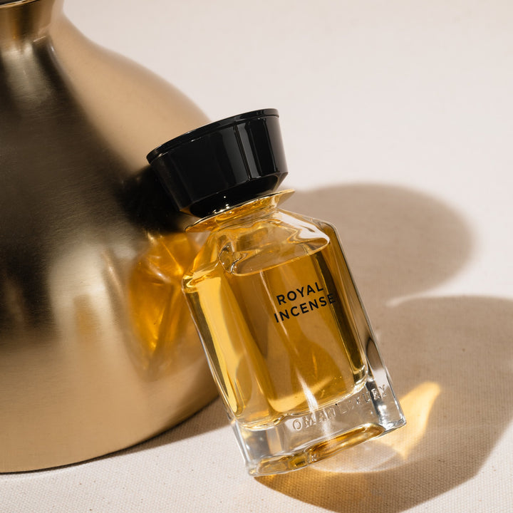 Oman Luxury Royal Incense Eau de Parfum bottle leaning on a brushed brass vessel in soft daylight