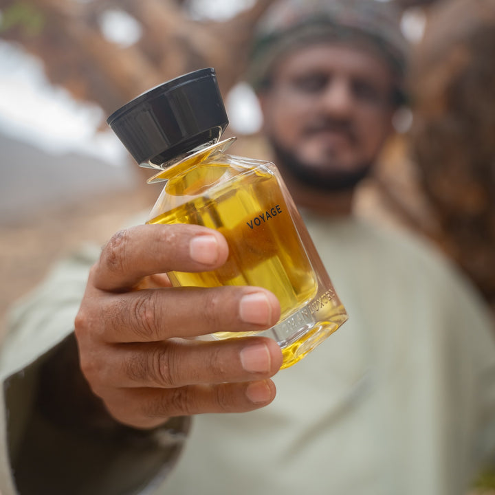 Oman Luxury Voyage Eau de Parfum bottle held out in a frankincense grove in Dhofar